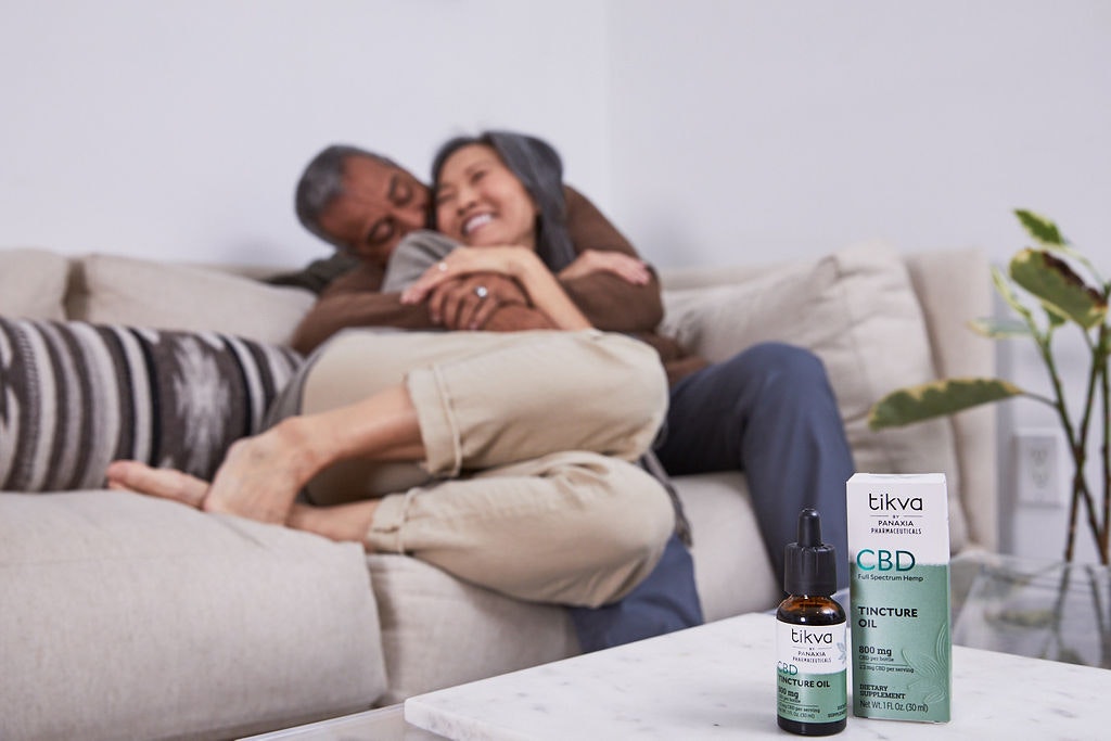Mature man and woman cuddling with tincture oil in foreground