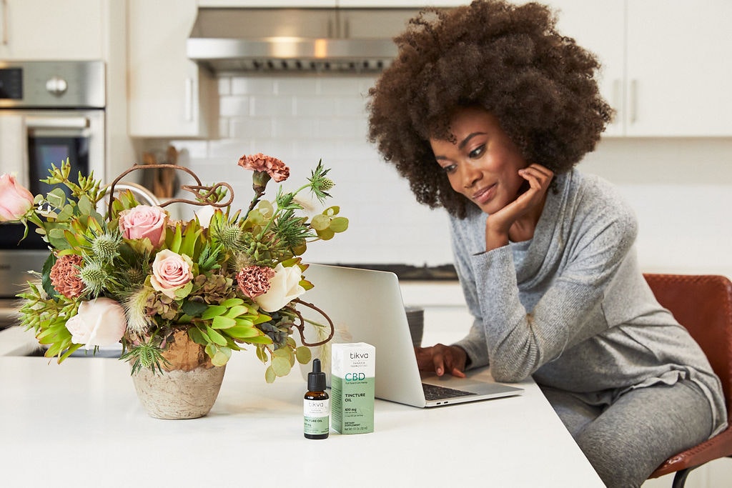 woman looking at computer in home office with Tikva CBD Tincture Oil