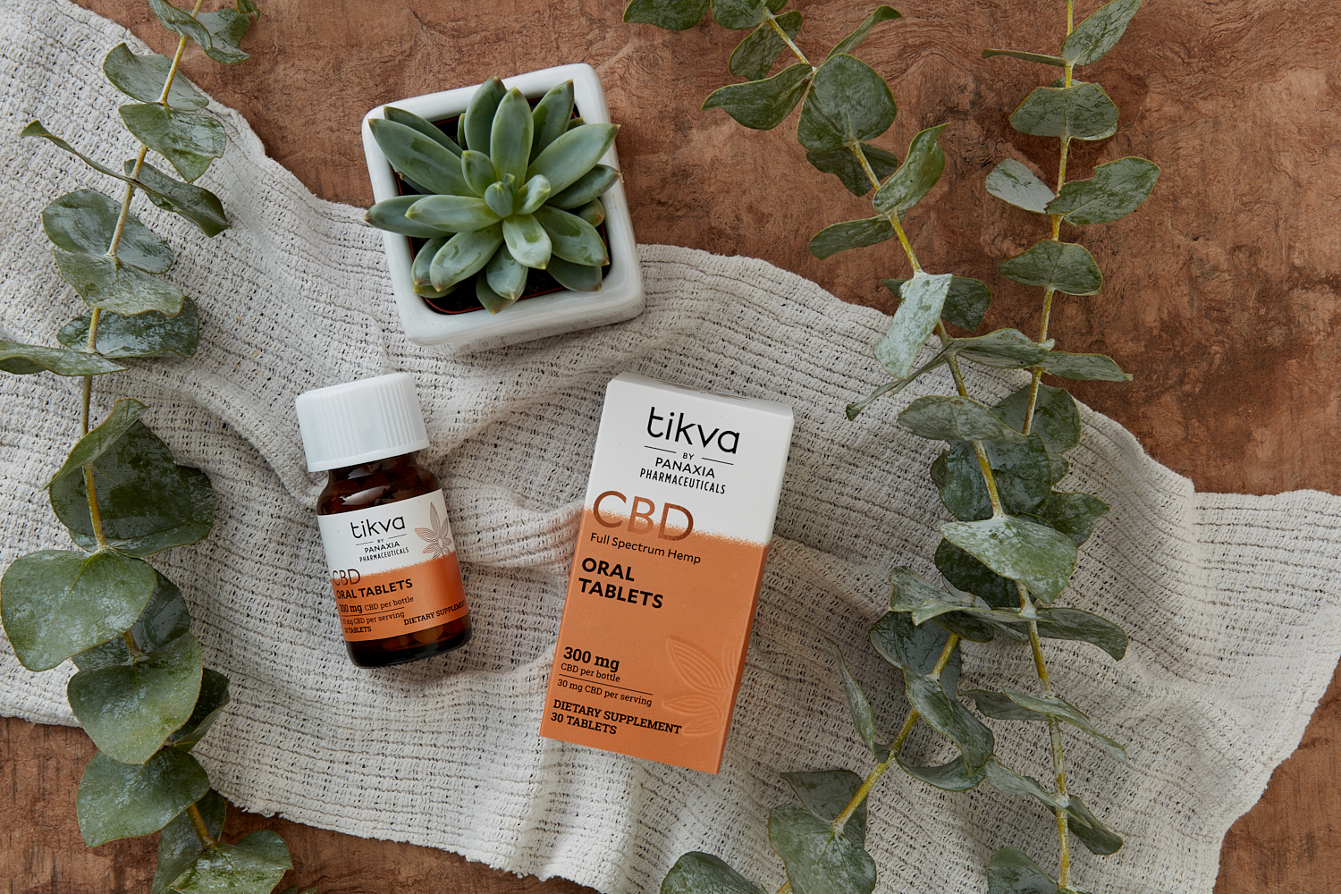Tikva CBD Oral Tablets Bottle and External Packaging with Cloth and Succulents in Background